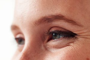 Primer plano del ojo de una mujer con arrugas finas bajo el párpado inferior y en la esquina exterior del ojo