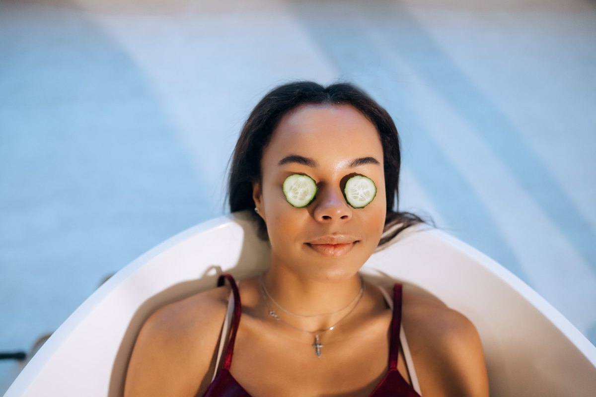 Mujer relajada en la bañera con dos rodajas de pepino sobre los ojos cerrados